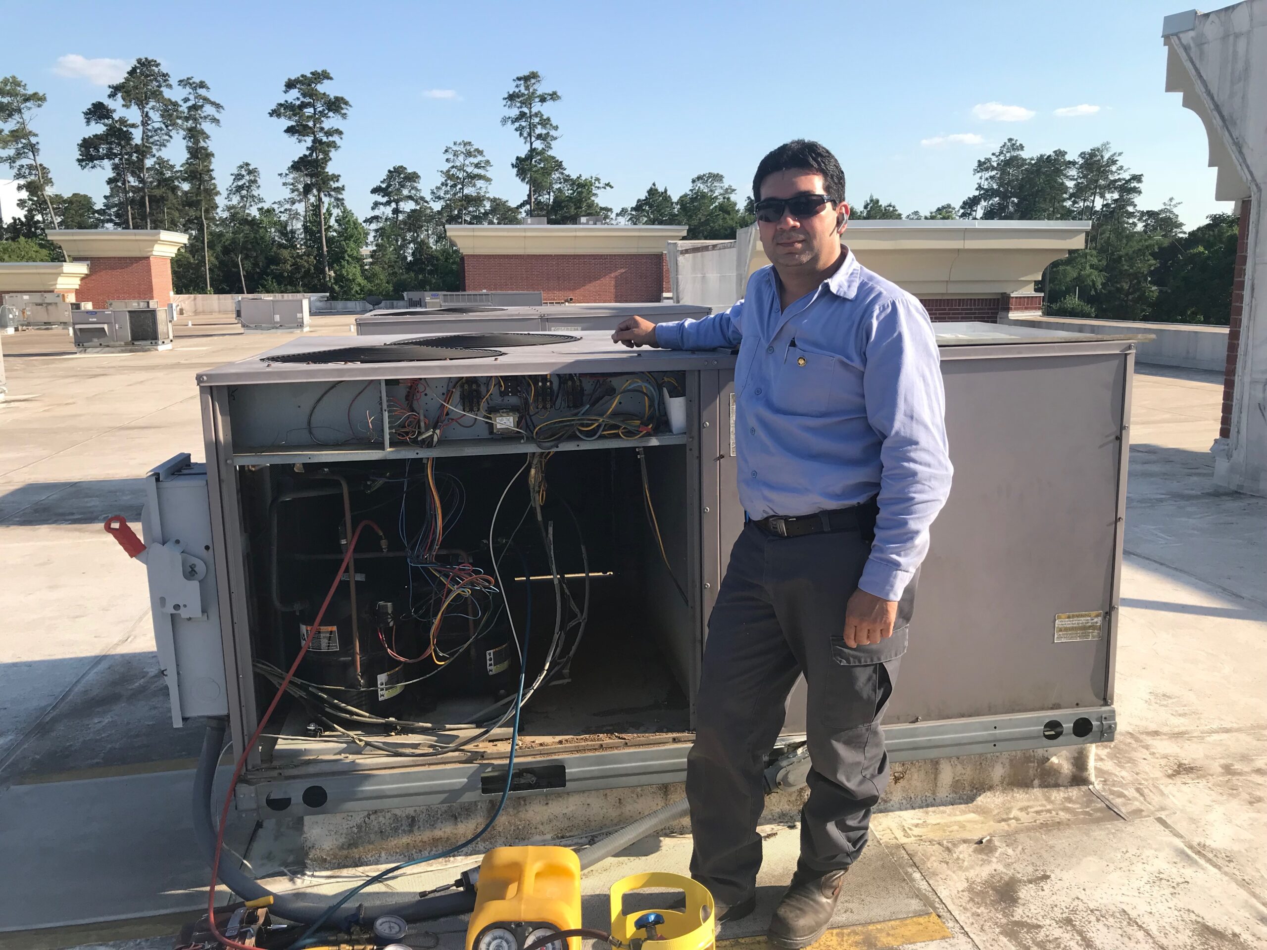 Jose servicing a commercial rooftop HVAC unit in Spring TX